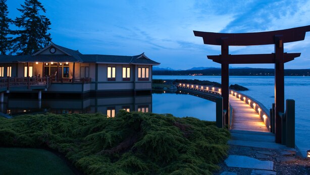 A waterfront property with a wooden deck, a torii gate, and a house with illuminated windows. - April Point Resort  (Quadra Island)