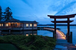 Una proprietà sul lungomare con un pontile in legno, un torii e una casa con finestre illuminate.