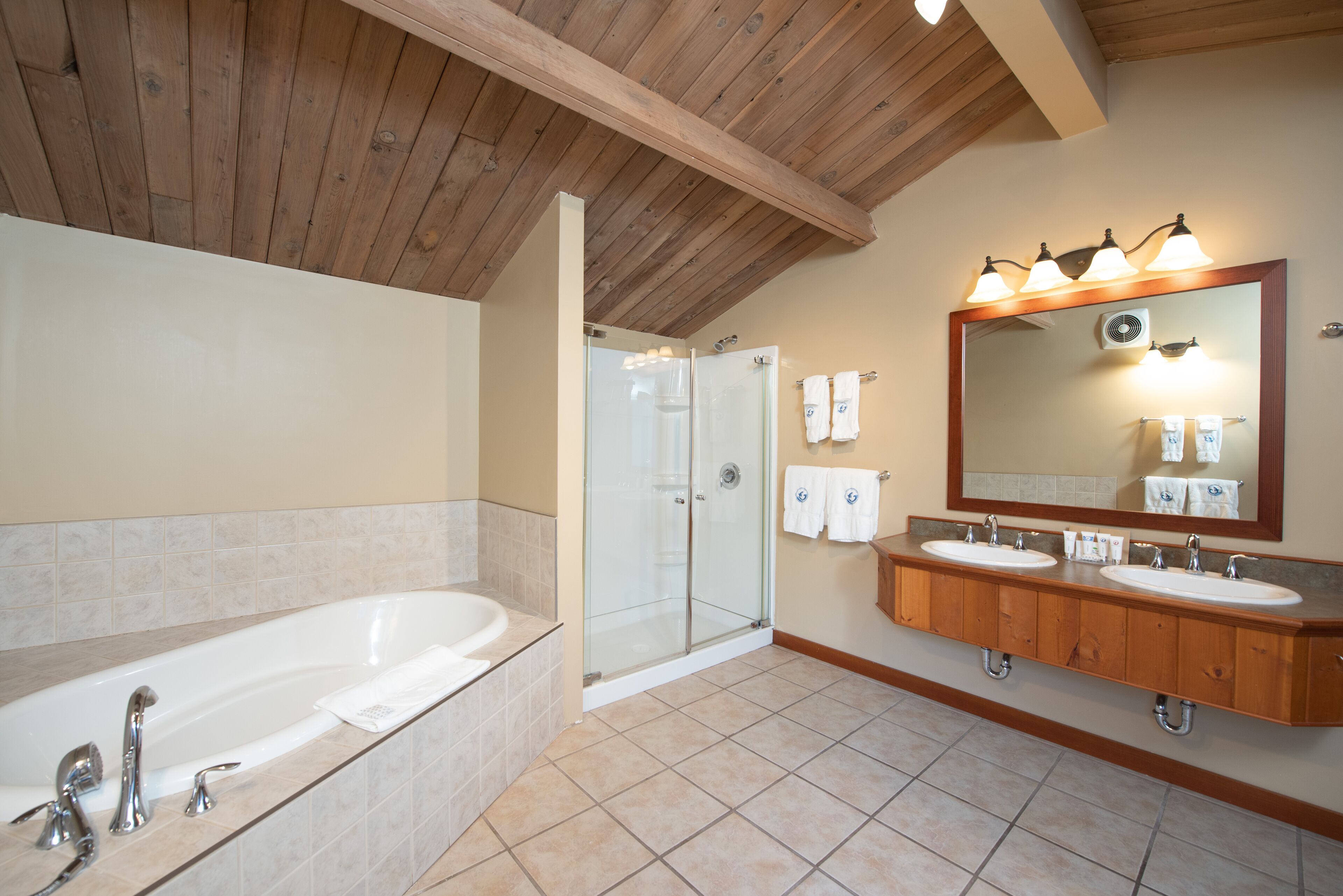 Une salle de bain dotée d’une grande baignoire, d’une douche à parois de verre et de meubles en bois.