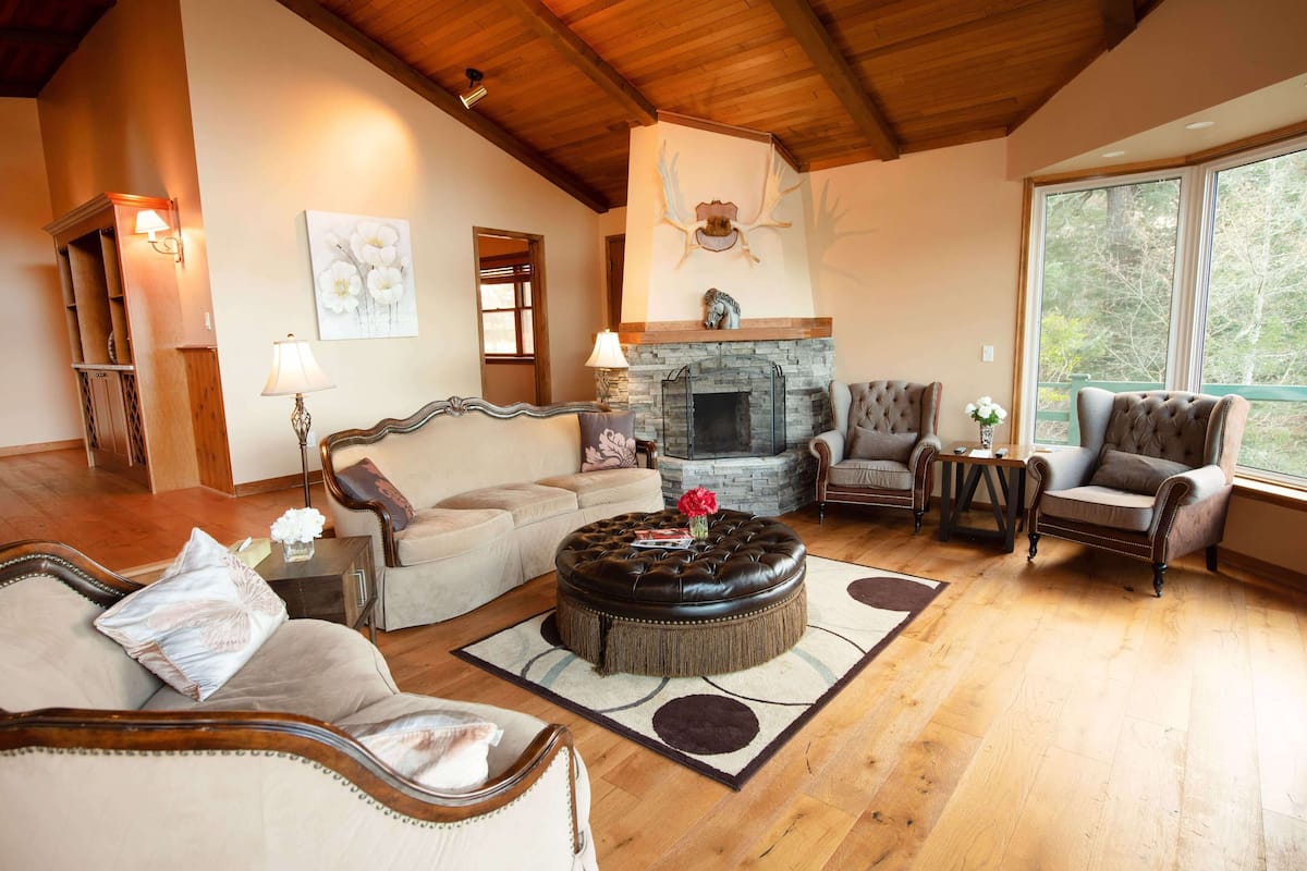 A cozy living room with a fireplace, leather ottoman, and comfortable seating.