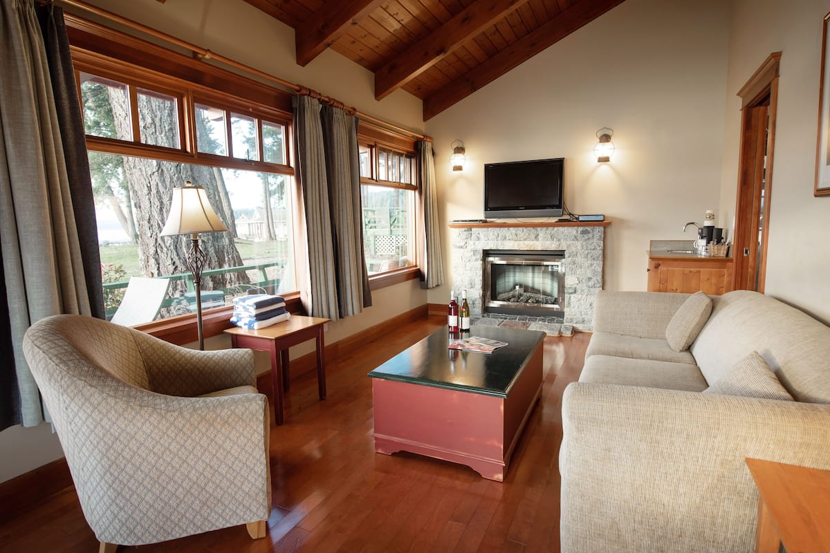 A living room with a fireplace, a sofa, a coffee table, and a TV mounted above the fireplace.