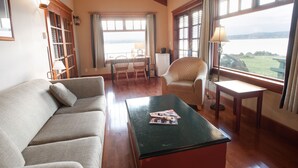 A living room with a sofa, a coffee table, a chair, a lamp, and a view of the water. - April Point Resort  (Quadra Island)