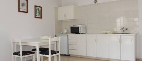 A small kitchen with white cabinets, a microwave, and a table with chairs.