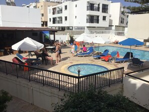 A poolside area with lounge chairs, umbrellas, and a swimming pool. - Florea Hotel Apartments (Ayia Napa)