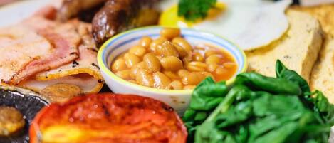 Un plato de comida con frijoles, tomates y vegetales verdes.