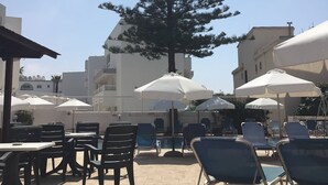 Un espace extérieur aménagé avec des tables et des chaises, un grand arbre et des parasols.