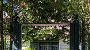 A wooden gate leading to a gravel path with a bench and potted plants. - Chiltern Inn (Bar Harbor)