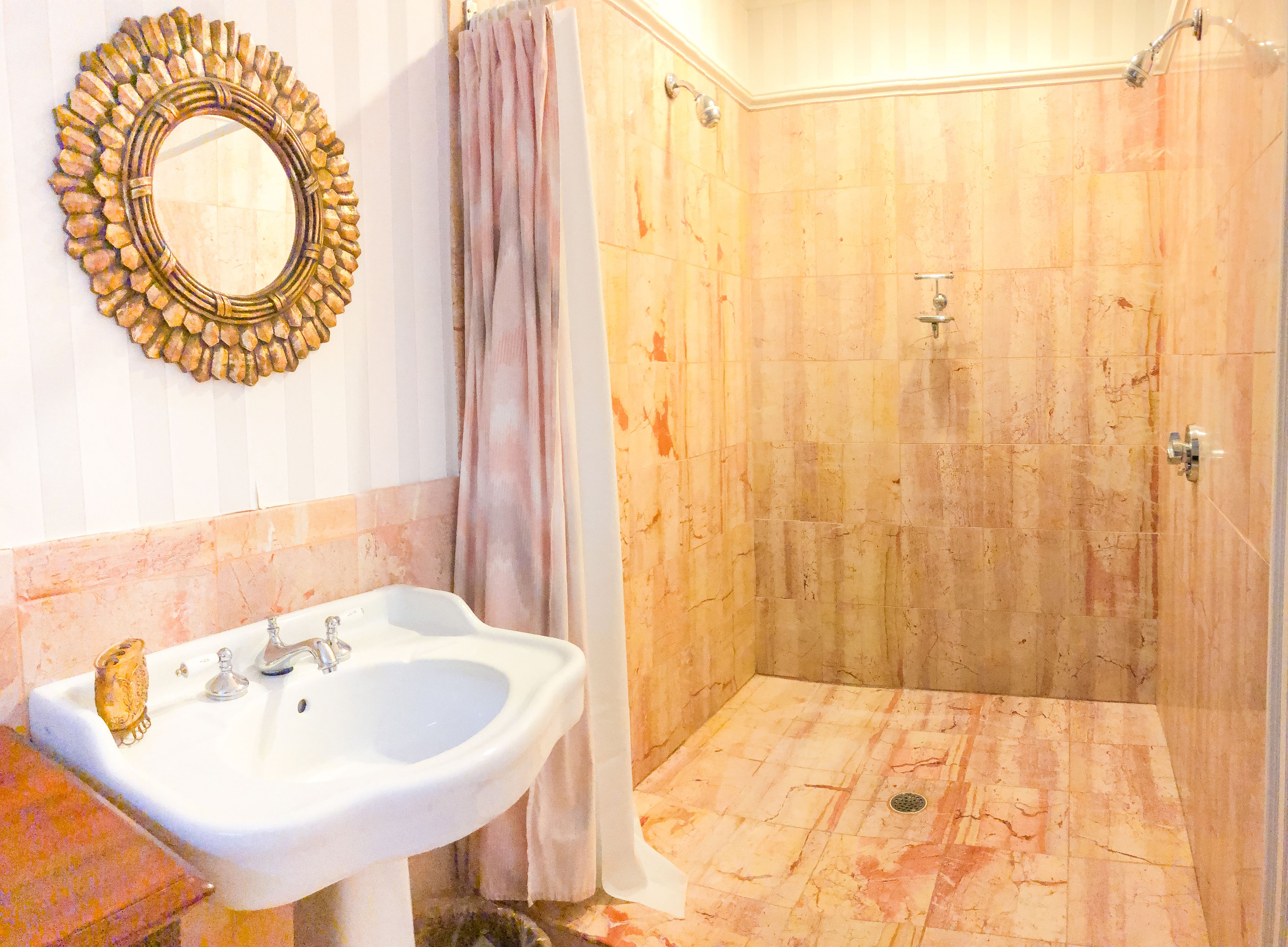 Ein Badezimmer mit Waschbecken, Spiegel, Dusche und gefliesten Wänden.