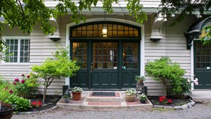 A traditional house with a green door, a small front porch, and potted plants. - Chiltern Inn (Bar Harbor)