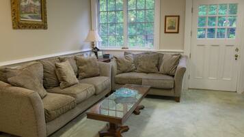 A living room with two beige sofas, a glass coffee table, and a white door with a window.