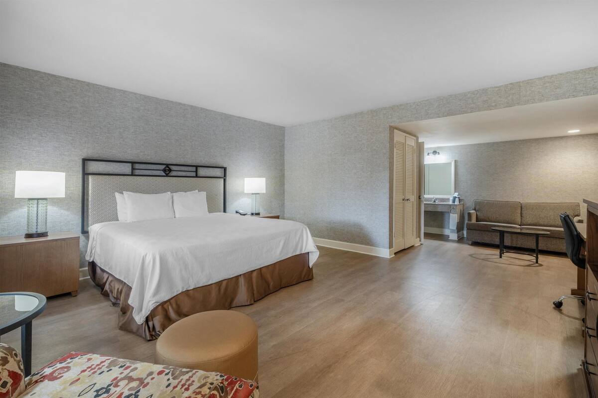 Een hotelkamer met een bed, nachtkastjes, een bureau, een stoel en een bank.