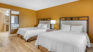 A hotel room with two beds, a mirror, and a nightstand with a lamp.