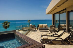 A poolside area with lounge chairs, a small pool, and a view of the ocean.