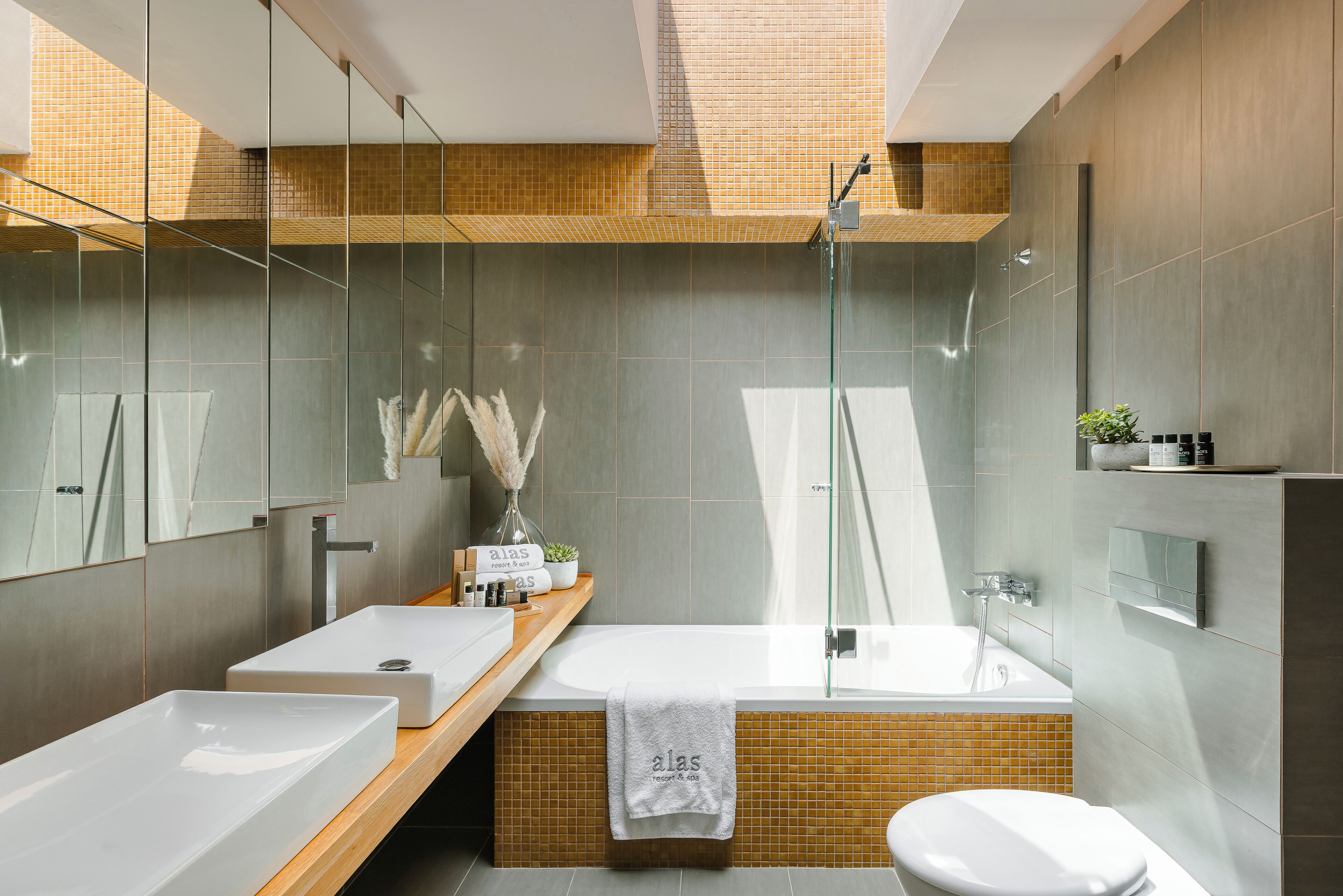 A modern bathroom with a large mirror, a sink, a bathtub, and a toilet.