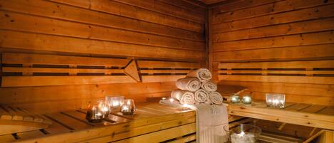 Una sauna de madera con bancos, toallas, velas y un bol de hielo.