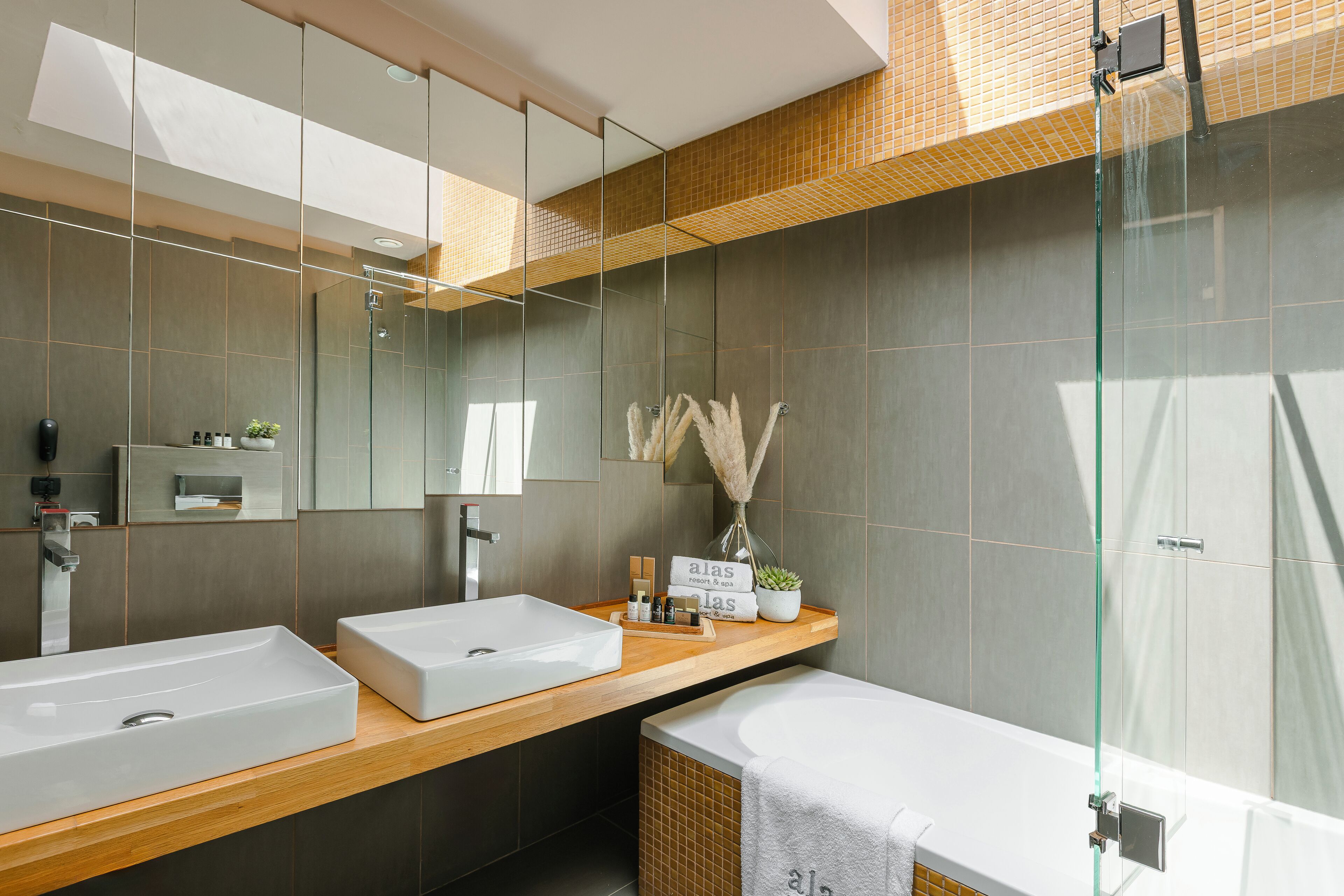Un baño moderno con dos lavamanos, cabina de ducha de vidrio y una bañera grande.