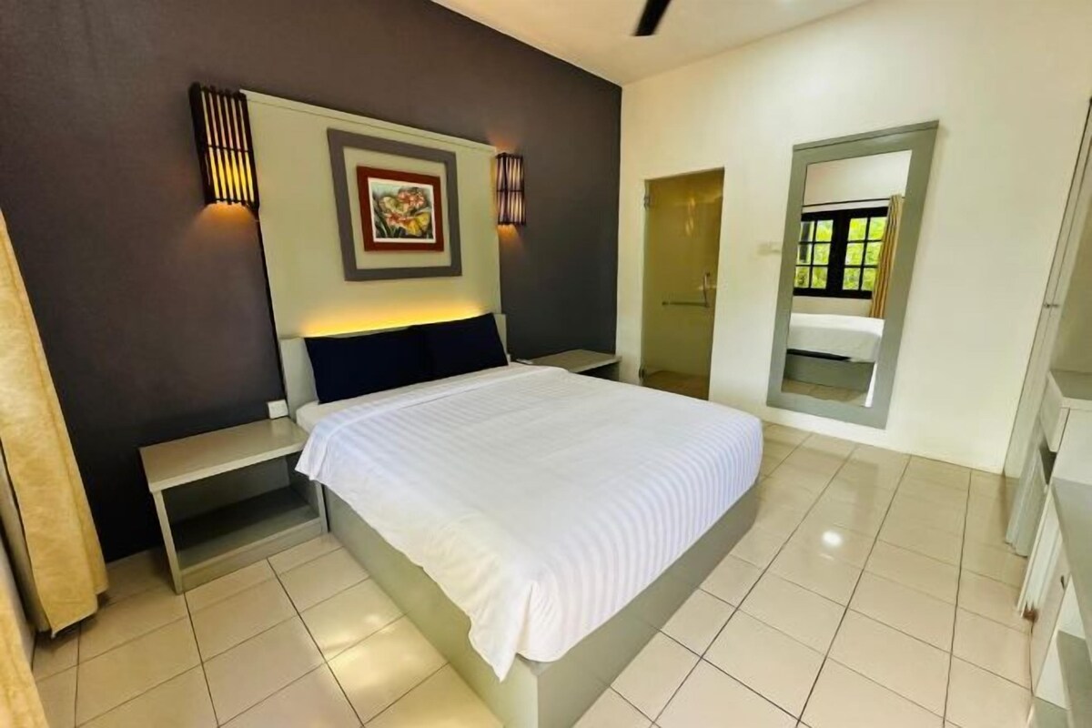 A bedroom with a bed, bedside tables, a wall-mounted picture, and a door with a window.