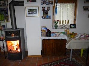 A cozy room with a wood-burning stove, a dining table with food, and various personal items on the walls.