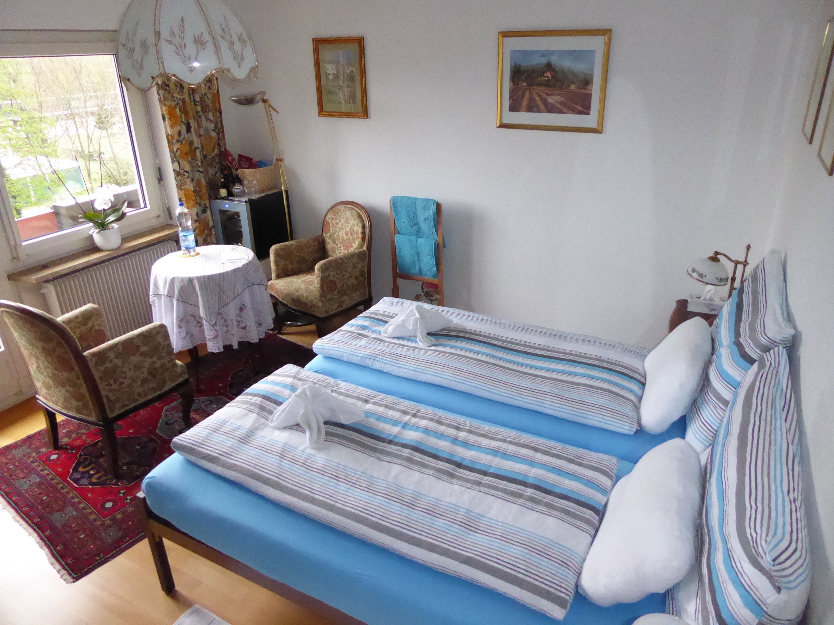 Ein Schlafzimmer mit einem Bett, einem Sessel, einem Tisch und einem Fenster.