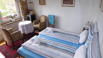 Ein Schlafzimmer mit einem Bett, einem Sessel, einem Tisch und einem Fenster.