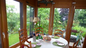A round table set for four with a white tablecloth, green placemats, and a bowl of bread. - B&B Pappelweg - 2 (Muttenz)