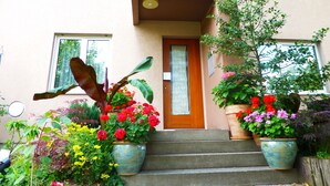 A two-story building with a front door, steps, and potted plants. - B&B Pappelweg - 2 (Muttenz)