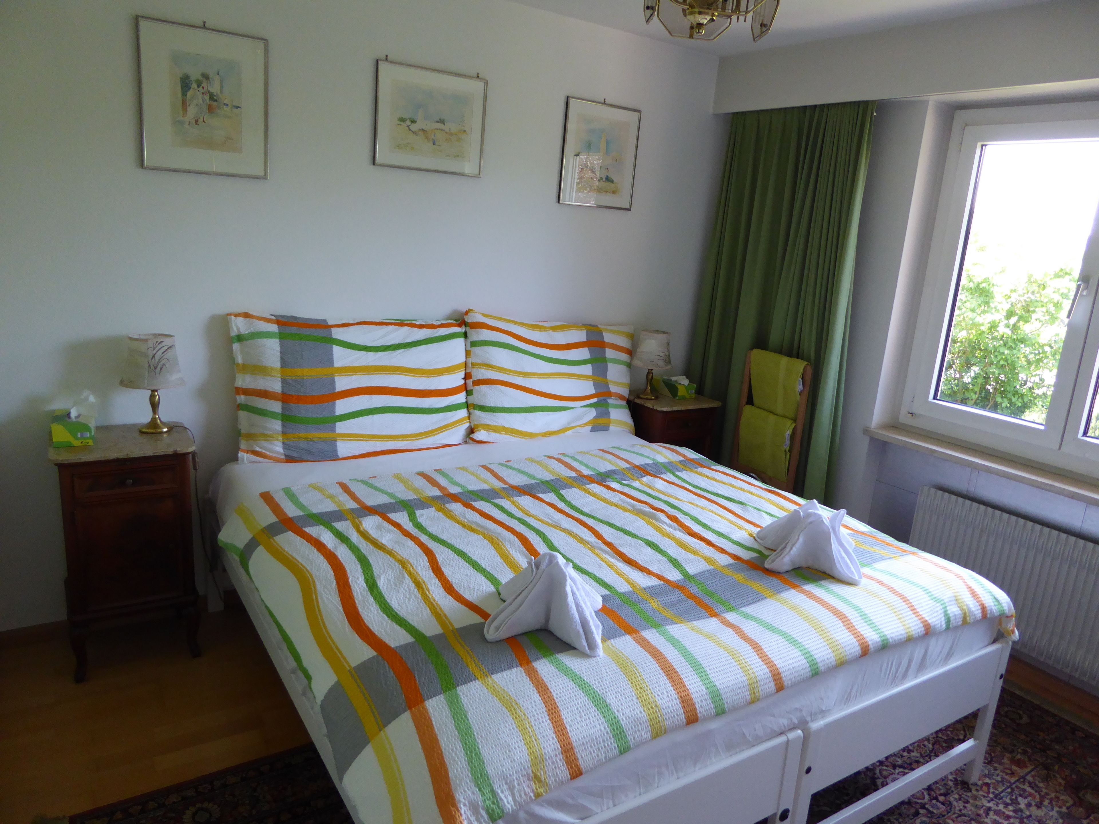 A hotel room with a bed, a nightstand, a chair, and a window with curtains.