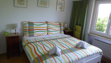 A hotel room with a bed, a nightstand, a chair, and a window with curtains.