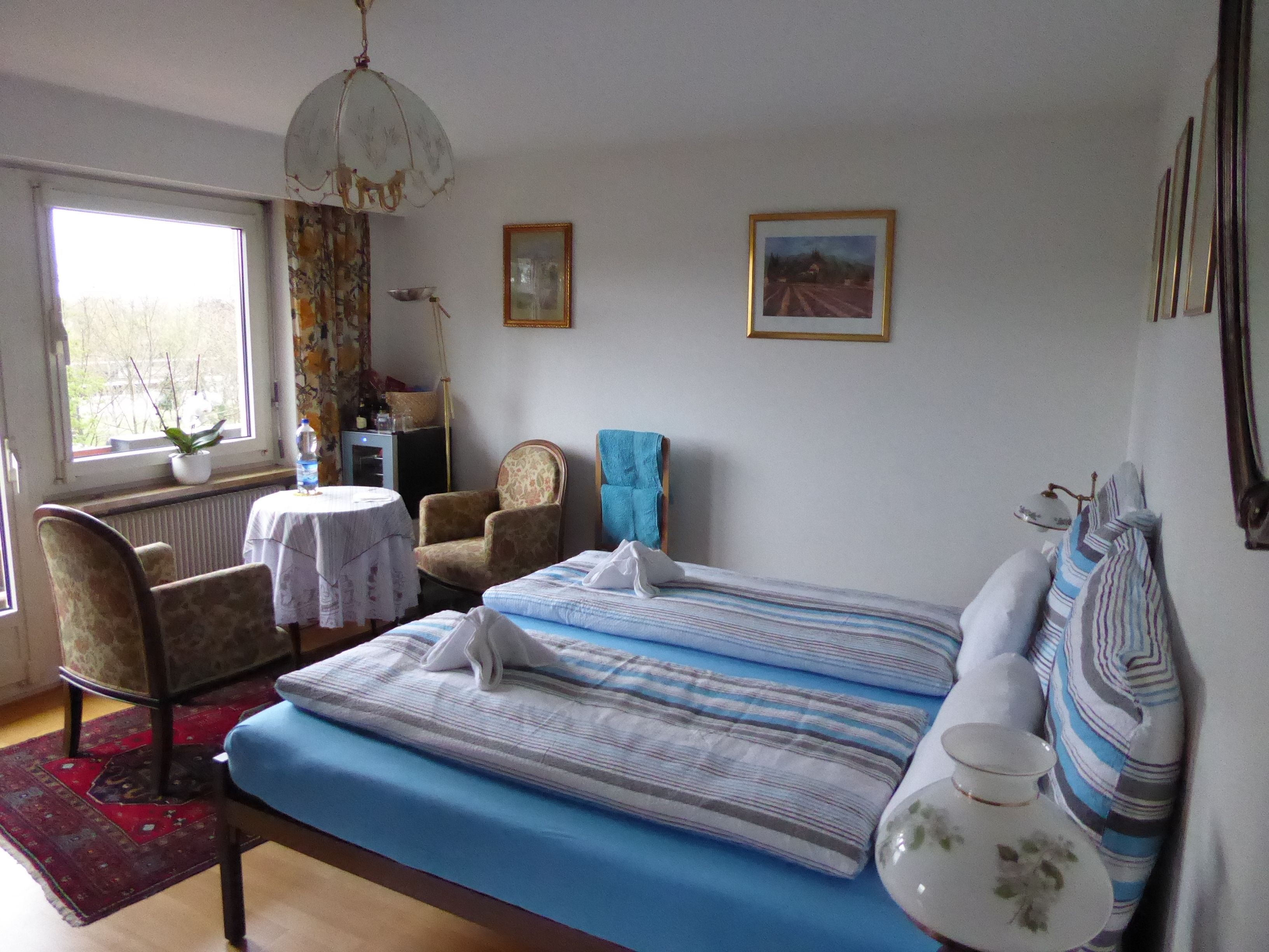 Une chambre à coucher avec un lit, une chaise, une table et une fenêtre.