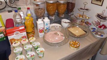 A buffet table with various food items, including biscuits, juices, dairy products, and desserts.