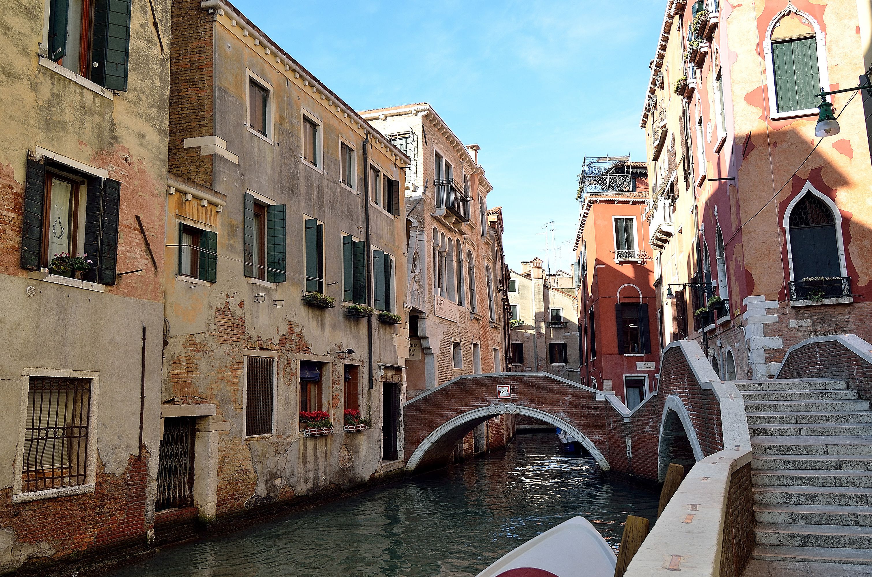 A narrow canal with a stone bridge and buildings on either side.