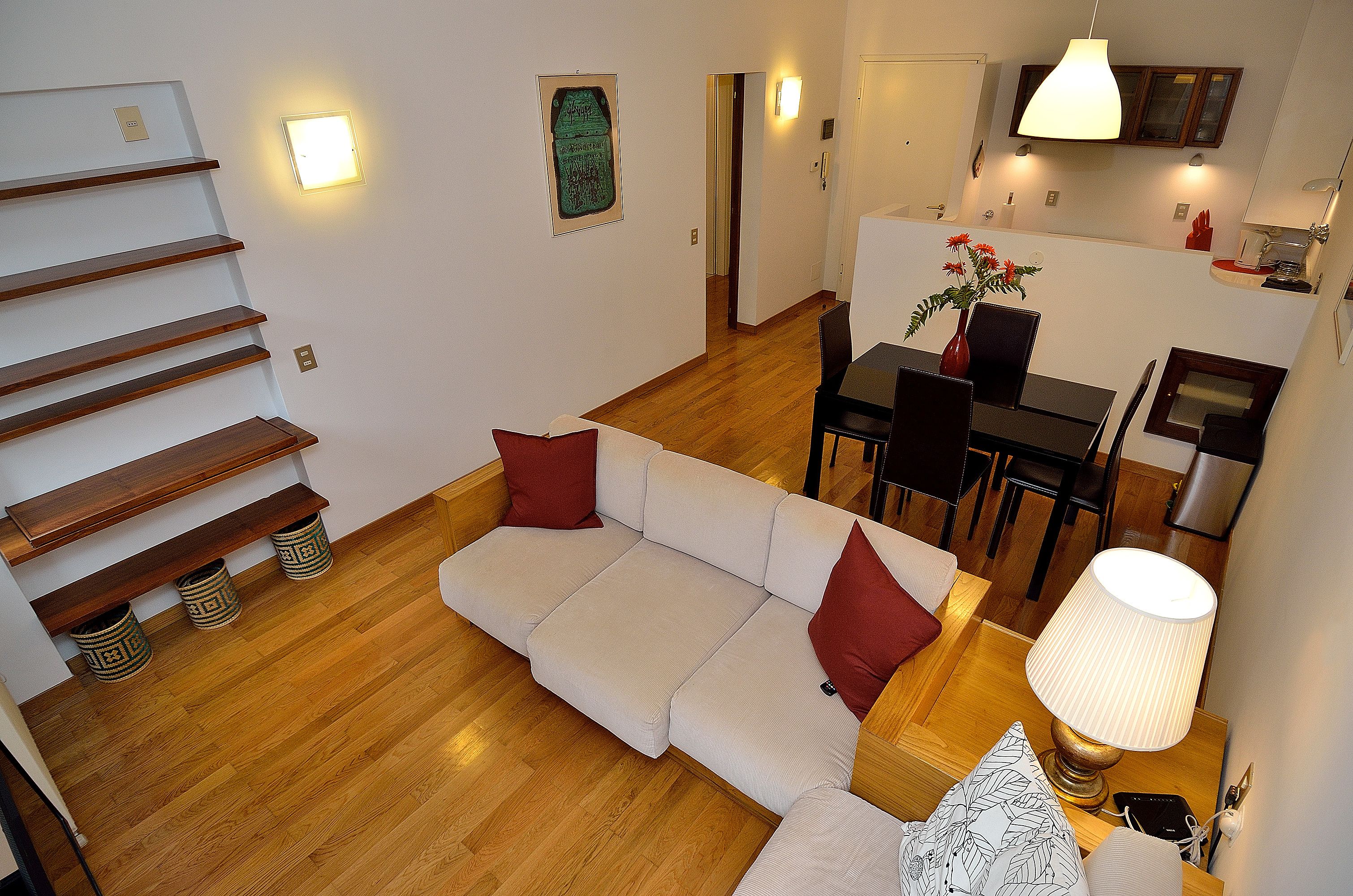 A modern living room with a sofa, dining table, and staircase.
