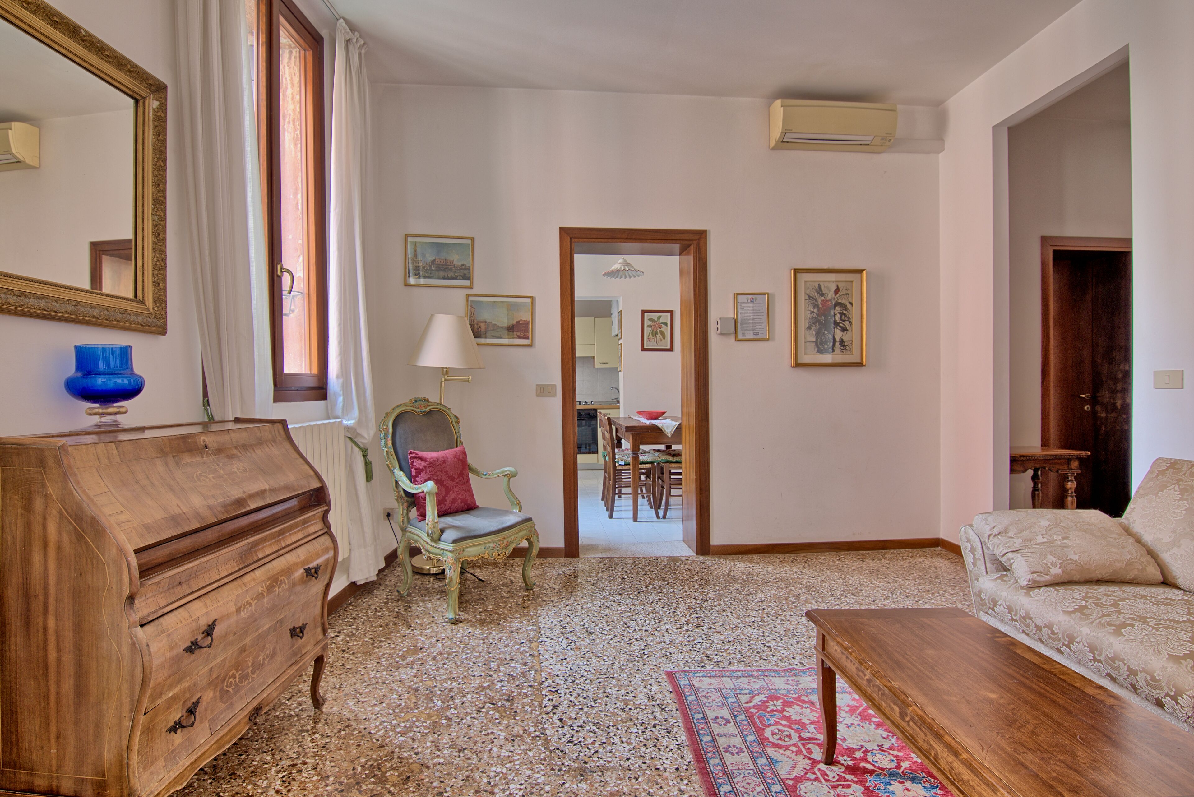 Quarto com cômoda de madeira, uma cadeira, um sofá e uma mesa de jantar.