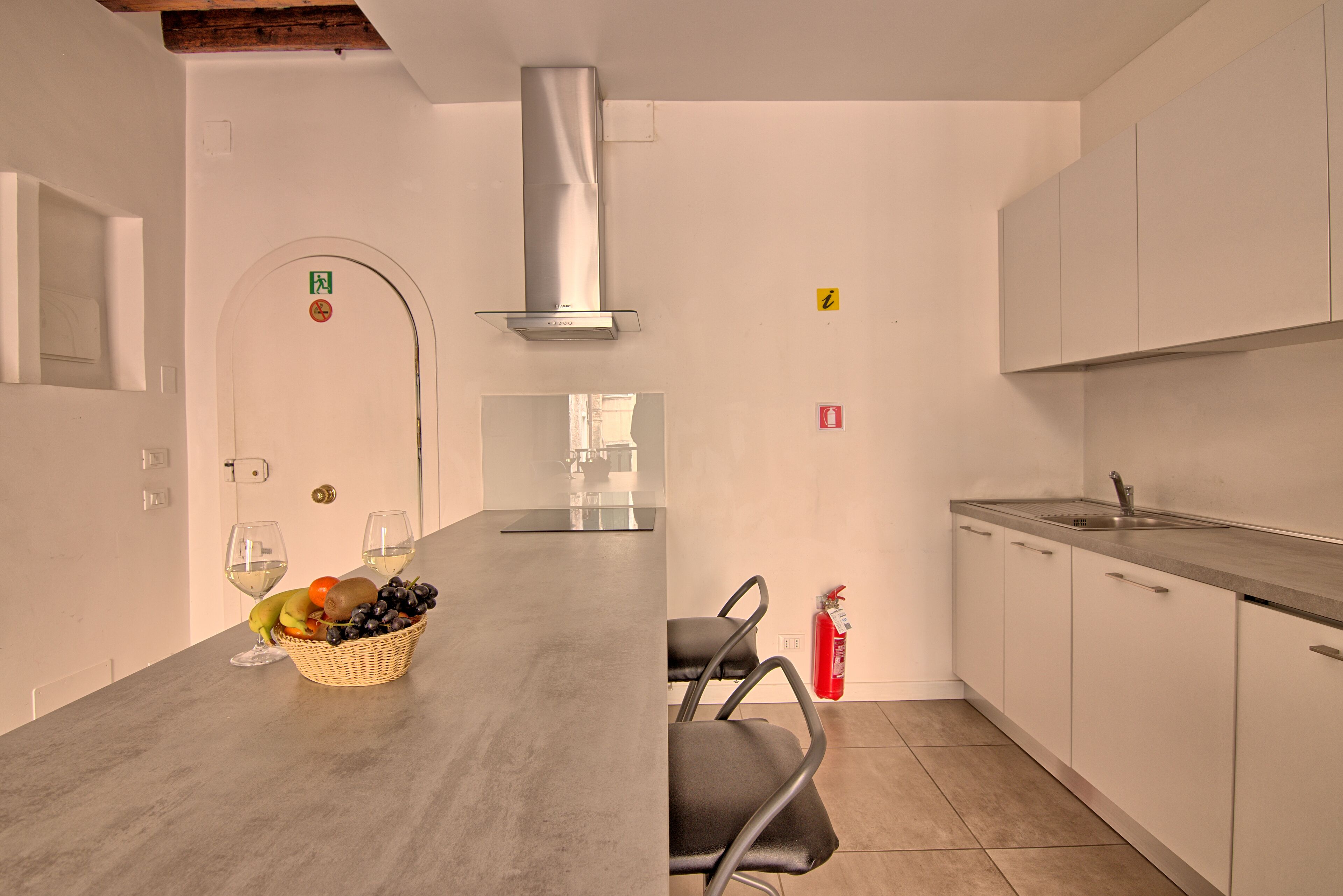 A modern kitchen with a central island, white cabinets, and a stainless steel range hood.