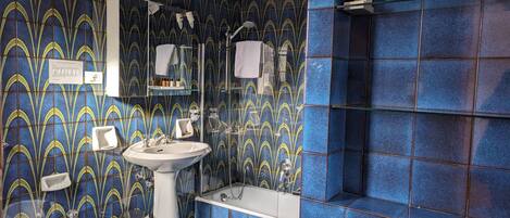 A bathroom with a blue and yellow patterned tile wall, a white sink, a bidet, and a bathtub.