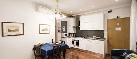 A modern kitchen with white cabinets, a dining table with chairs, and a chandelier.