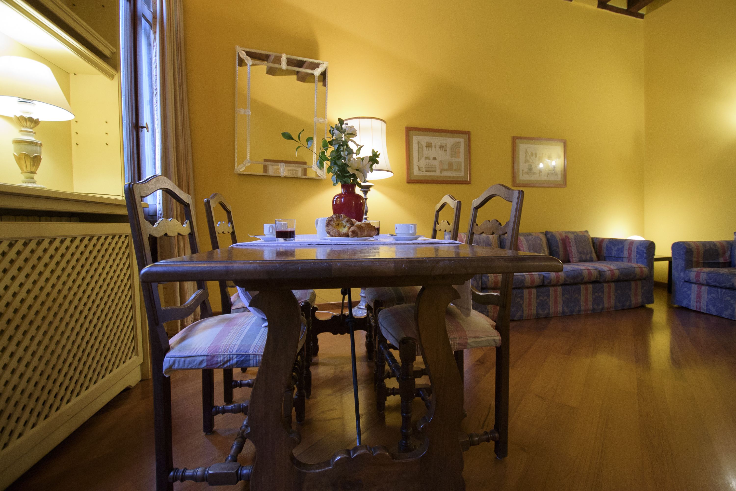 Un coin repas avec une table en bois, des chaises, un vase de fleurs et un canapé.