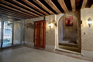 Una stanza con travi a vista in legno, un'ampia porta in legno e un poster appeso al muro.