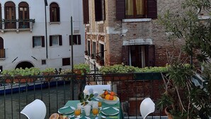 Eine Terrasse mit Frühstückstisch, mit Blick auf einen Kanal und historische Gebäude.