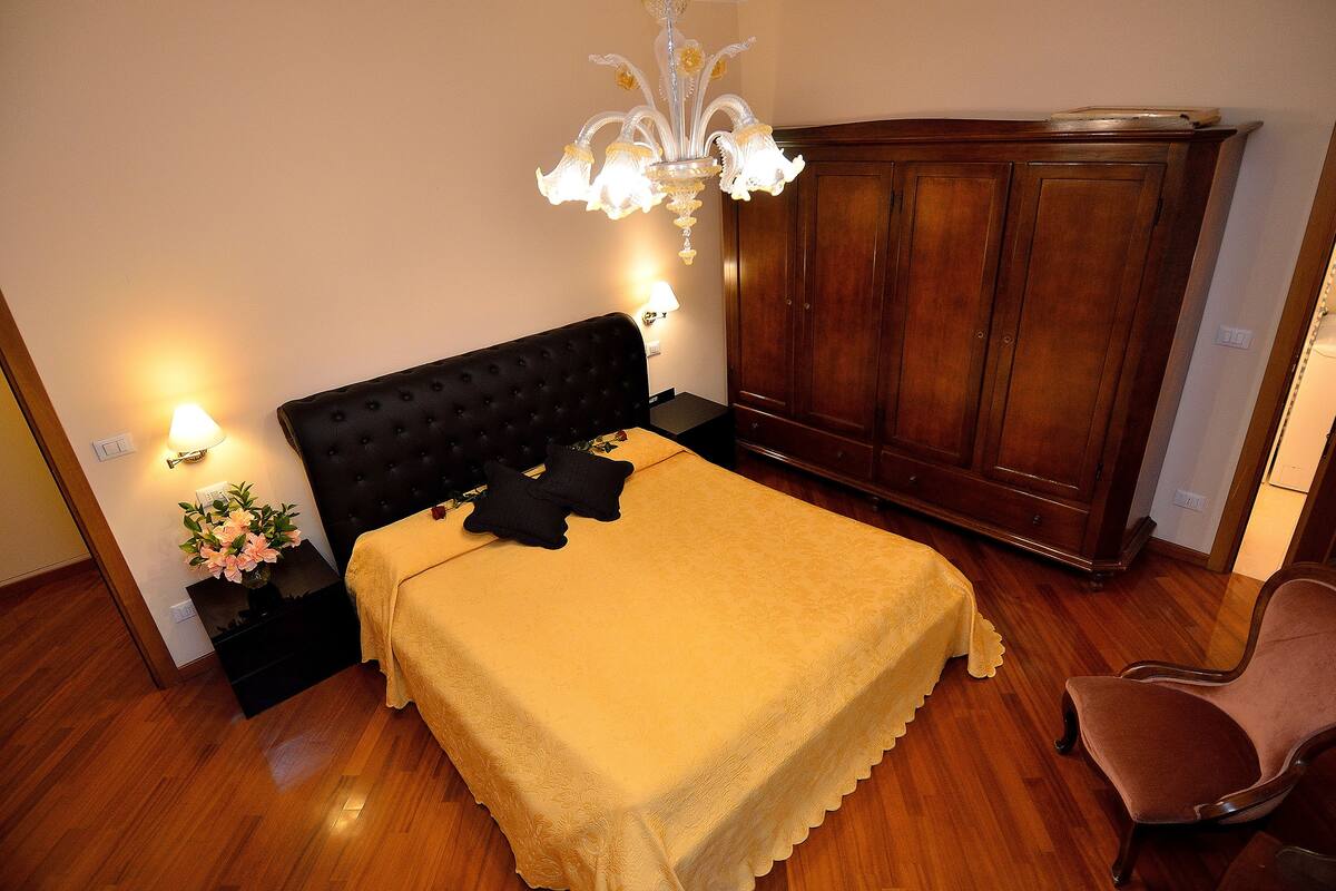 A bedroom with a bed, a nightstand, a lamp, a dresser, and a chair.