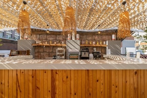 Eine Bar mit Holzböden, einem Grill und hängenden Lampen.