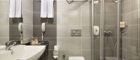A modern bathroom with a sink, mirror, towel rack, toilet, and glass-enclosed shower.
