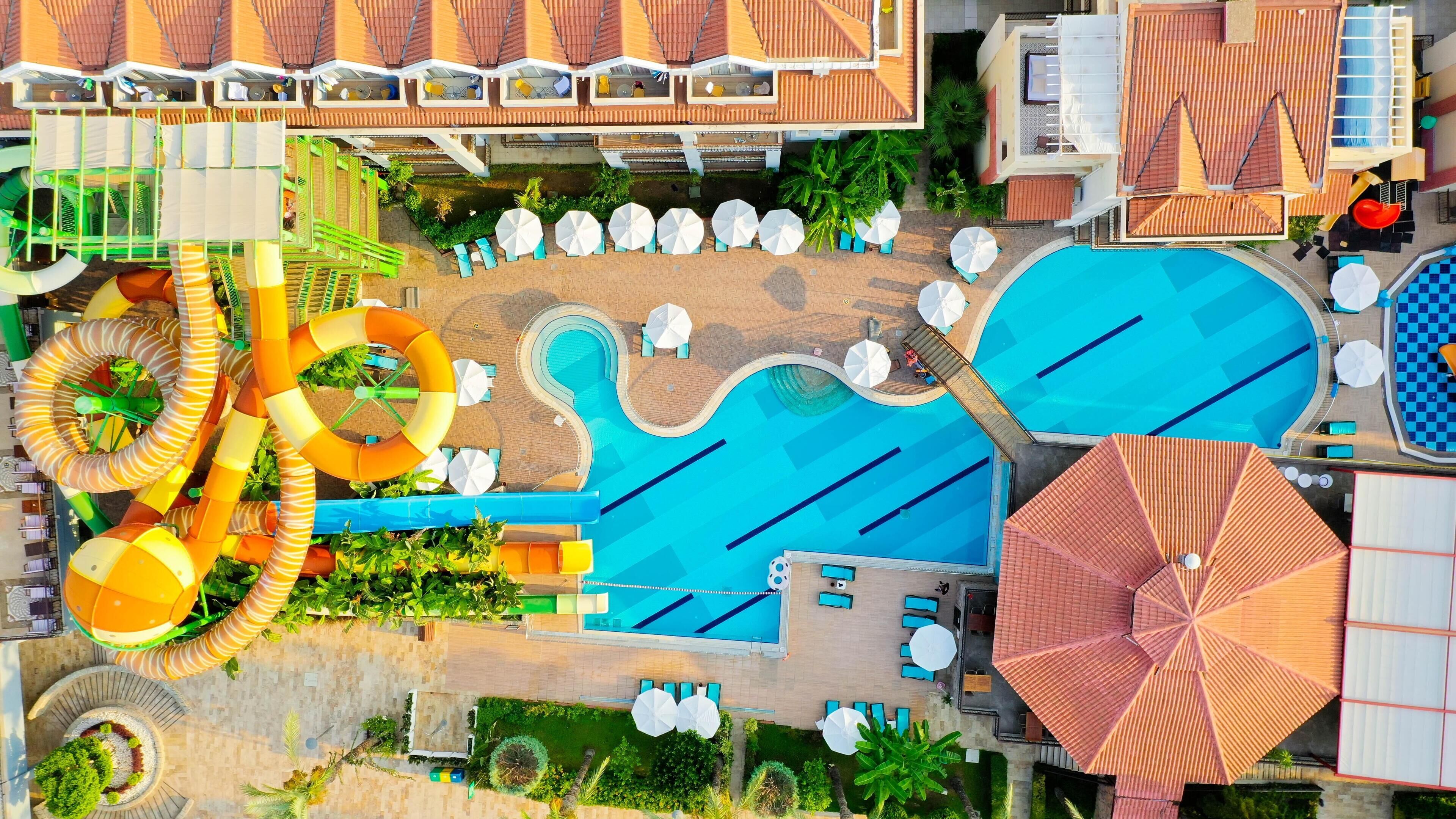 An aerial view of a resort with multiple swimming pools, water slides, and sun loungers.