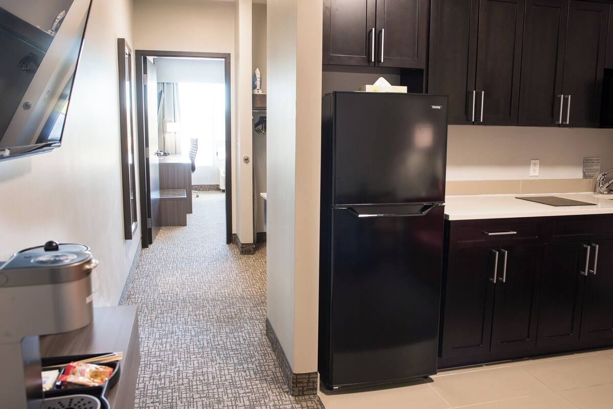 A modern kitchen with dark cabinets, a black refrigerator, and a countertop with a sink.
