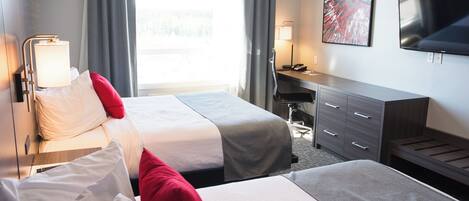 Habitación de hotel con dos camas, un escritorio, una silla, un televisor y una ventana con cortinas.