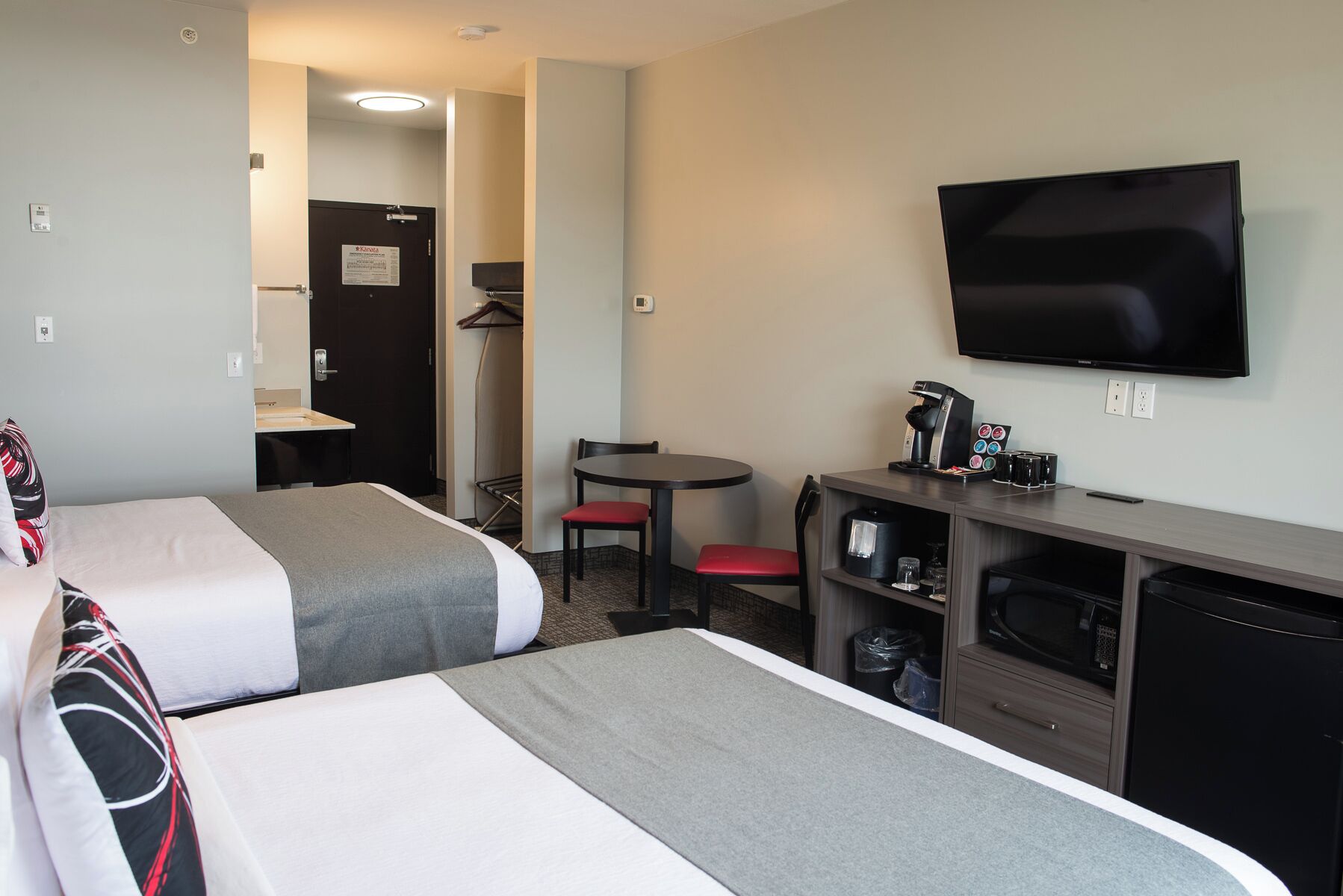 A hotel room with two beds, a desk with a coffee maker, a TV, and a microwave.