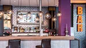 Een bar met een bakstenen muur, hangende lampen en een spiegel.