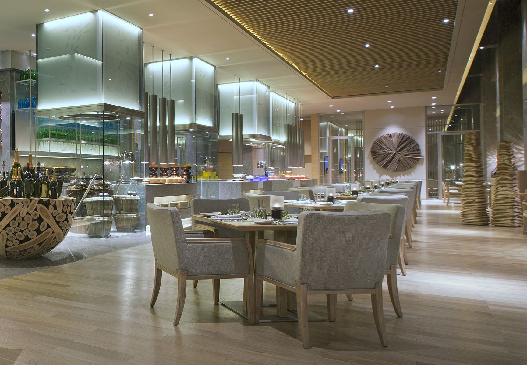 Ein modernes Restaurant-Interieur mit einem langen Esstisch, Stühlen und einer zentralen Leuchte.