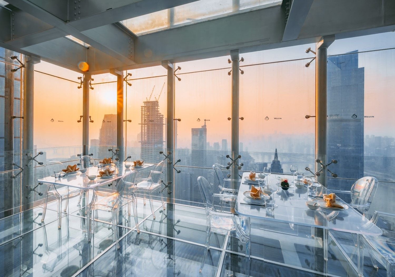 A high-rise dining area with a city view, modern furniture, and a glass table.