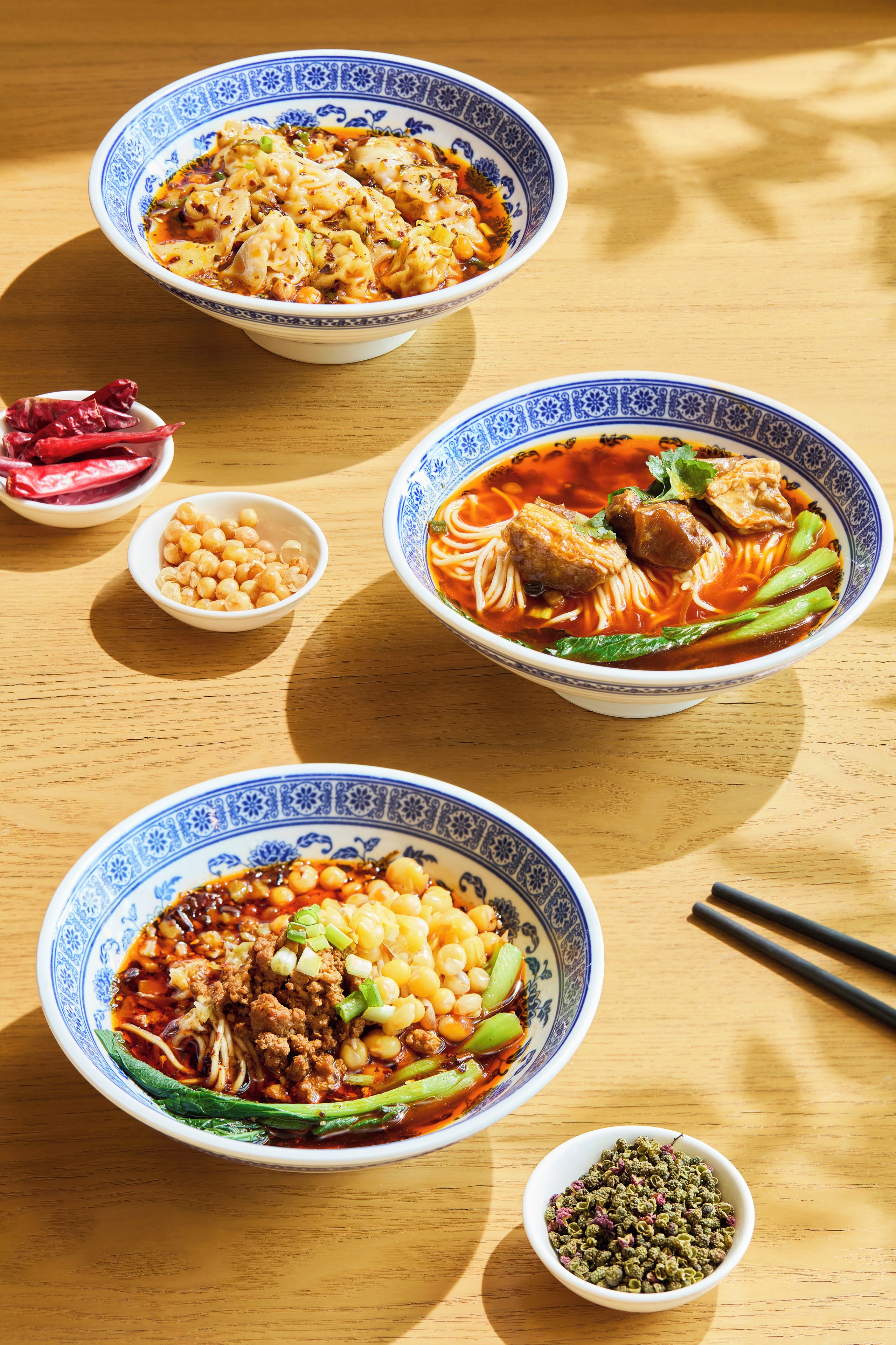 Three bowls of food on a wooden table.